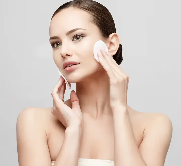 A woman touching her cheek after applying skincare